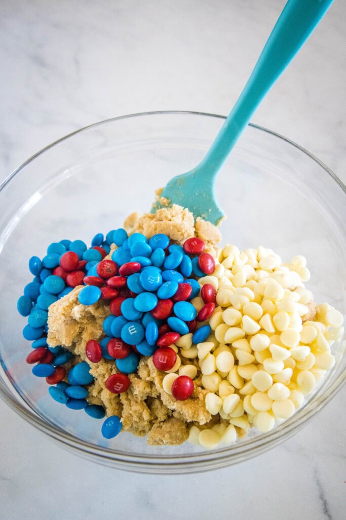 adding M&M's and white chocolate chips to cookie dough