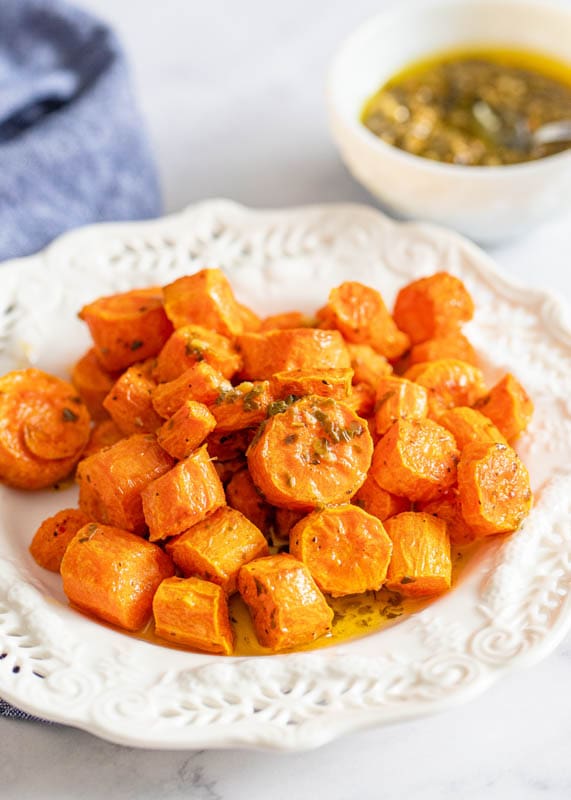 roasted carrots on white plate with pesto butter