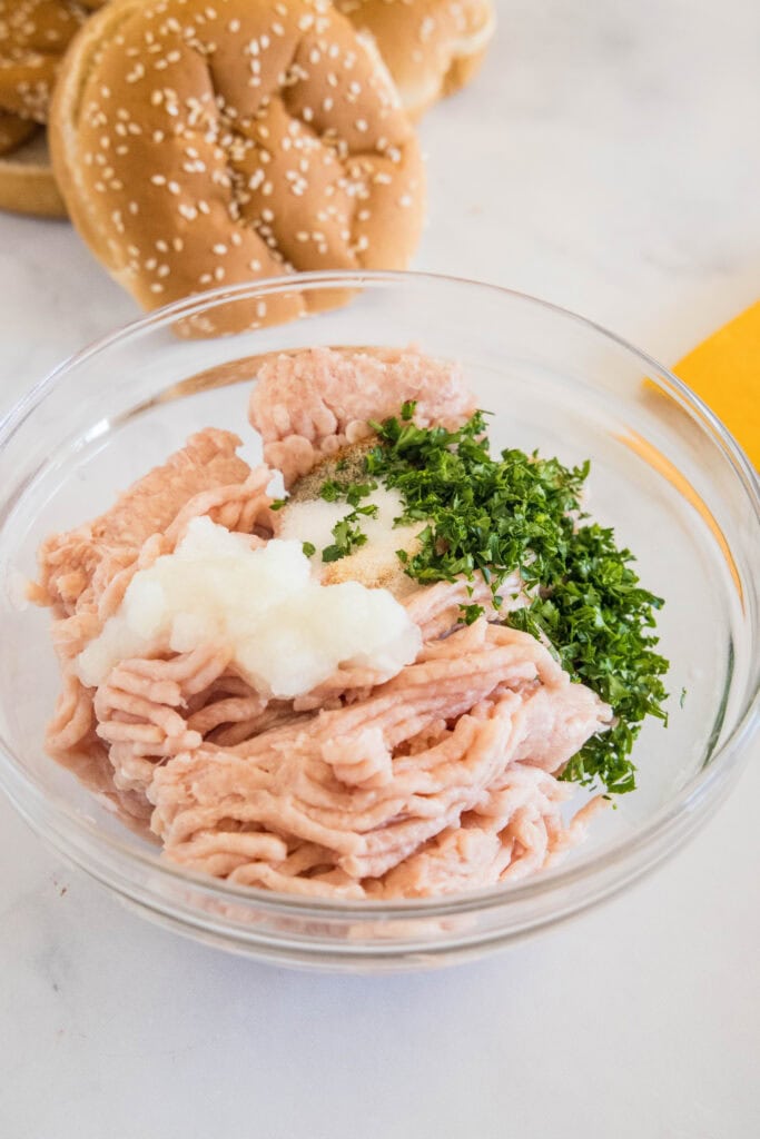 Chicken burger patty ingredients combined in a glass bowl.