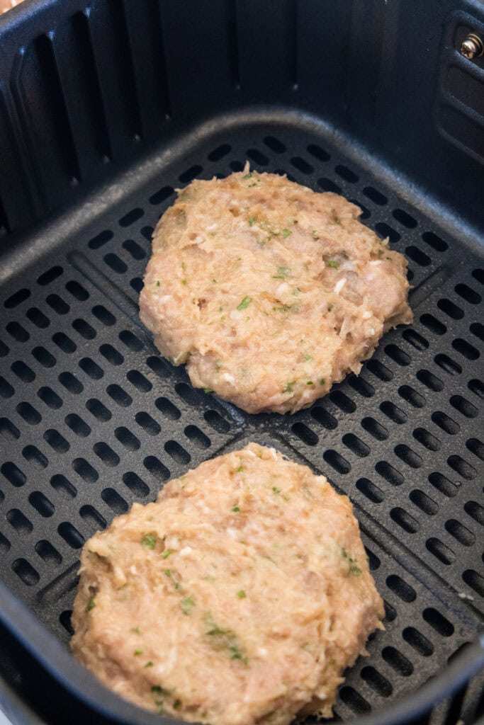 Two chicken patties inside the air fryer basket.