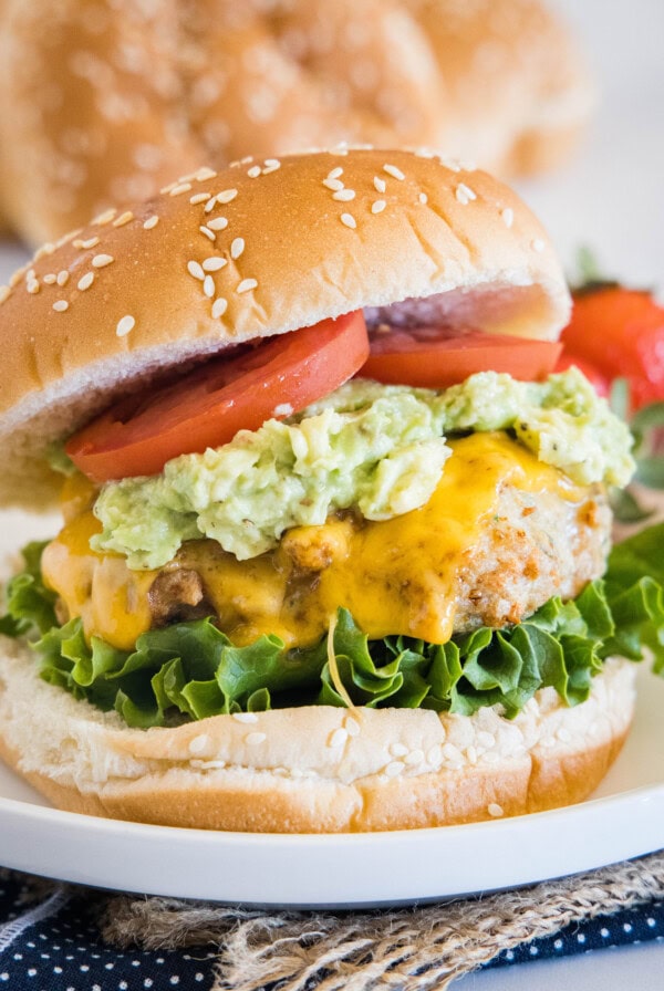 An air fryer chicken burger stacked with all the fixings on a white plate.