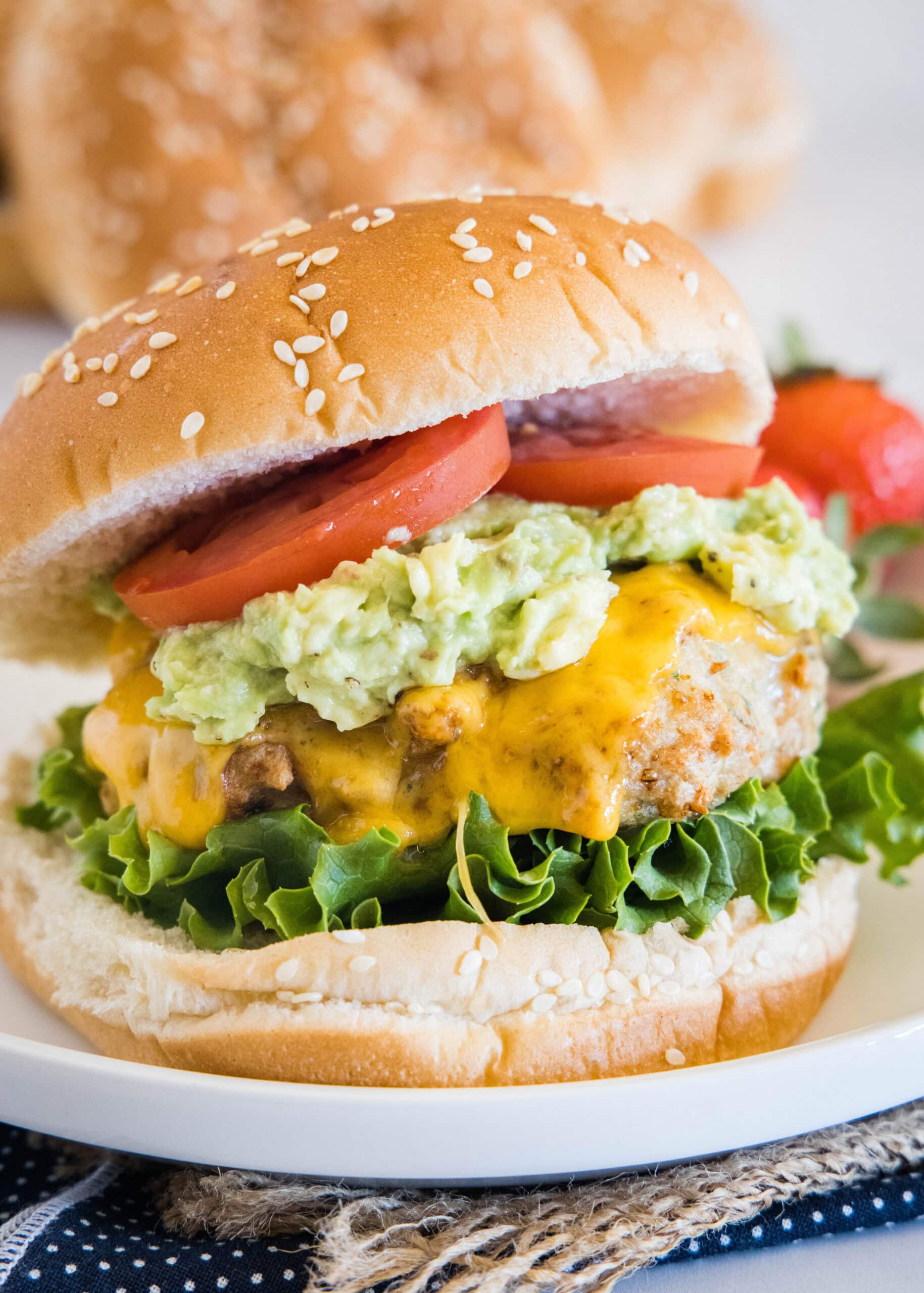 An air fryer chicken burger stacked with all the fixings on a white plate.