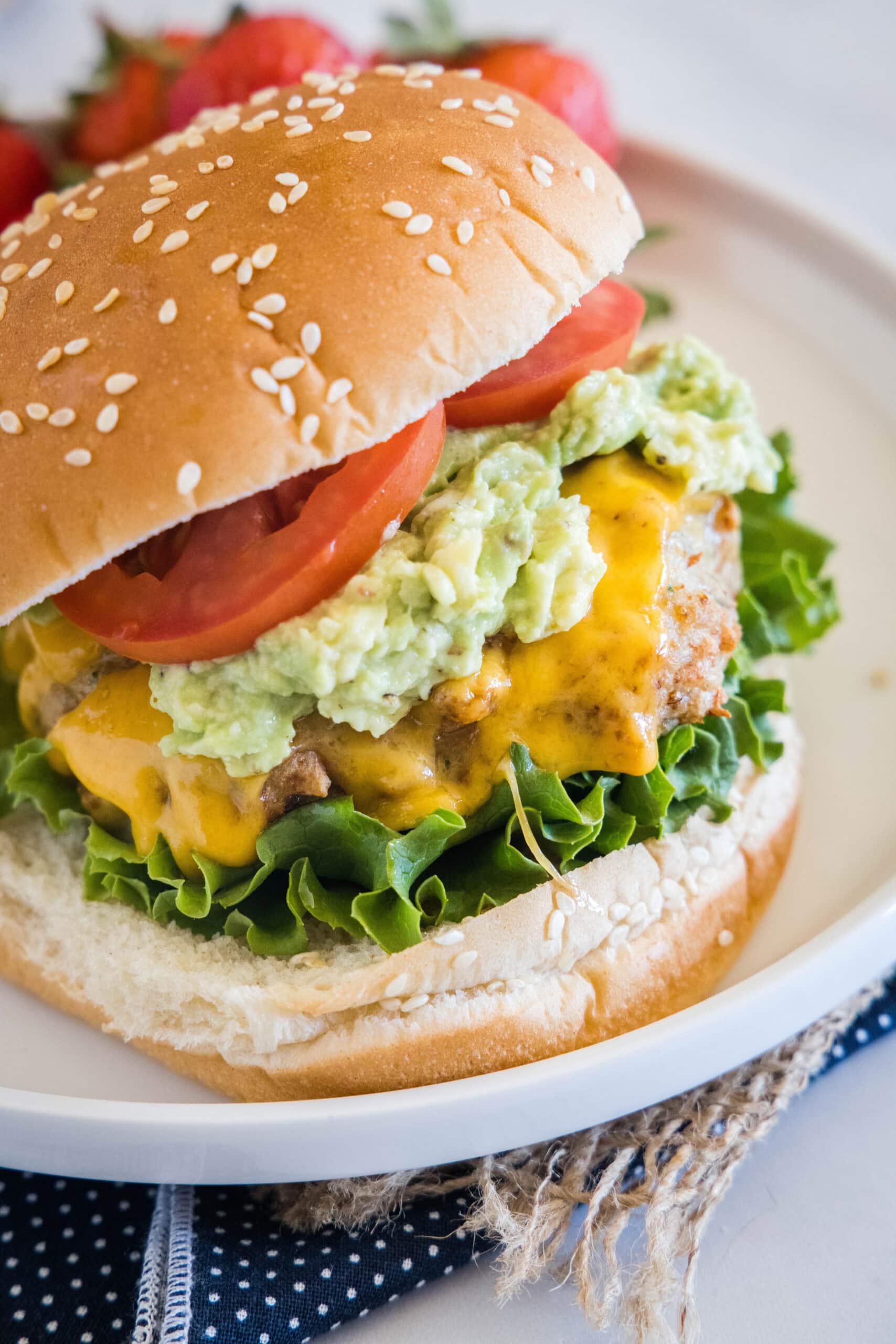 An air fryer chicken burger stacked with all the fixings on a white plate.