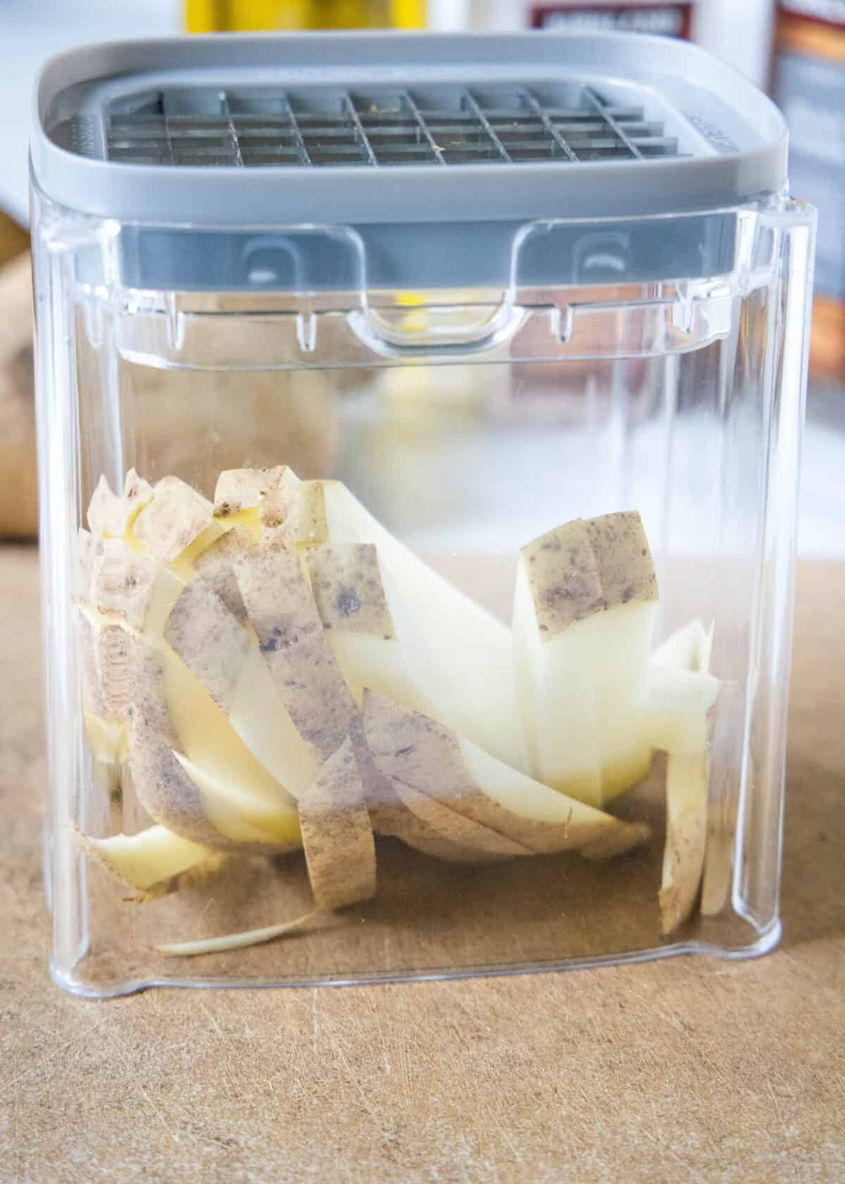 Potatoes cut into fries inside a potato cutter.