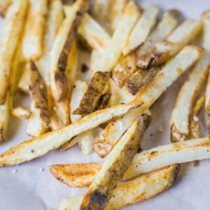 Close up of homemade air fryer French fries on a sheet of parchment paper.