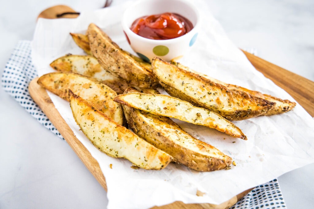 paper with cooked potato wedges on it