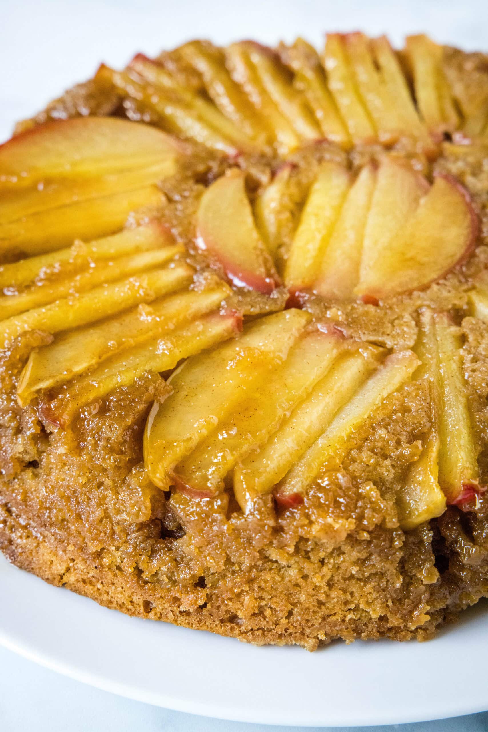 A whole apple upside down cake on a white plate.
