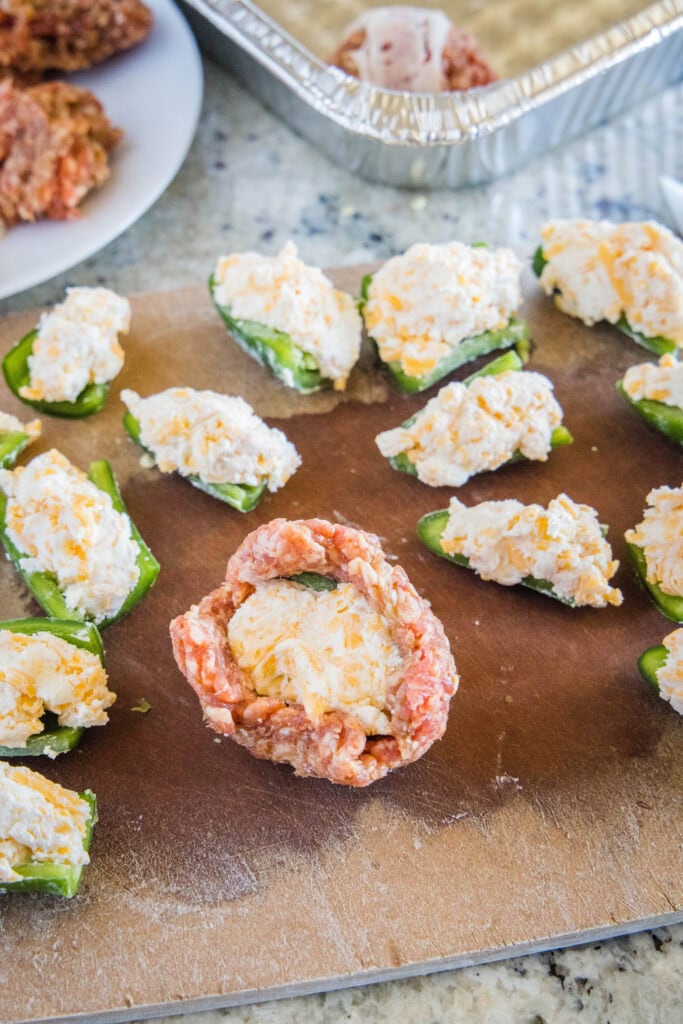wrapping sausage around jalapenos stuffed with cheese