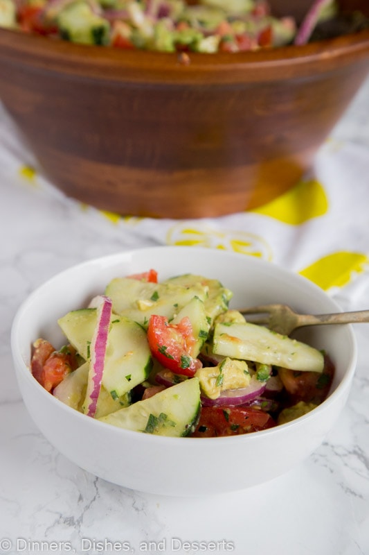 A close up of a bowl of food on a plate, with Salad and Cucumber