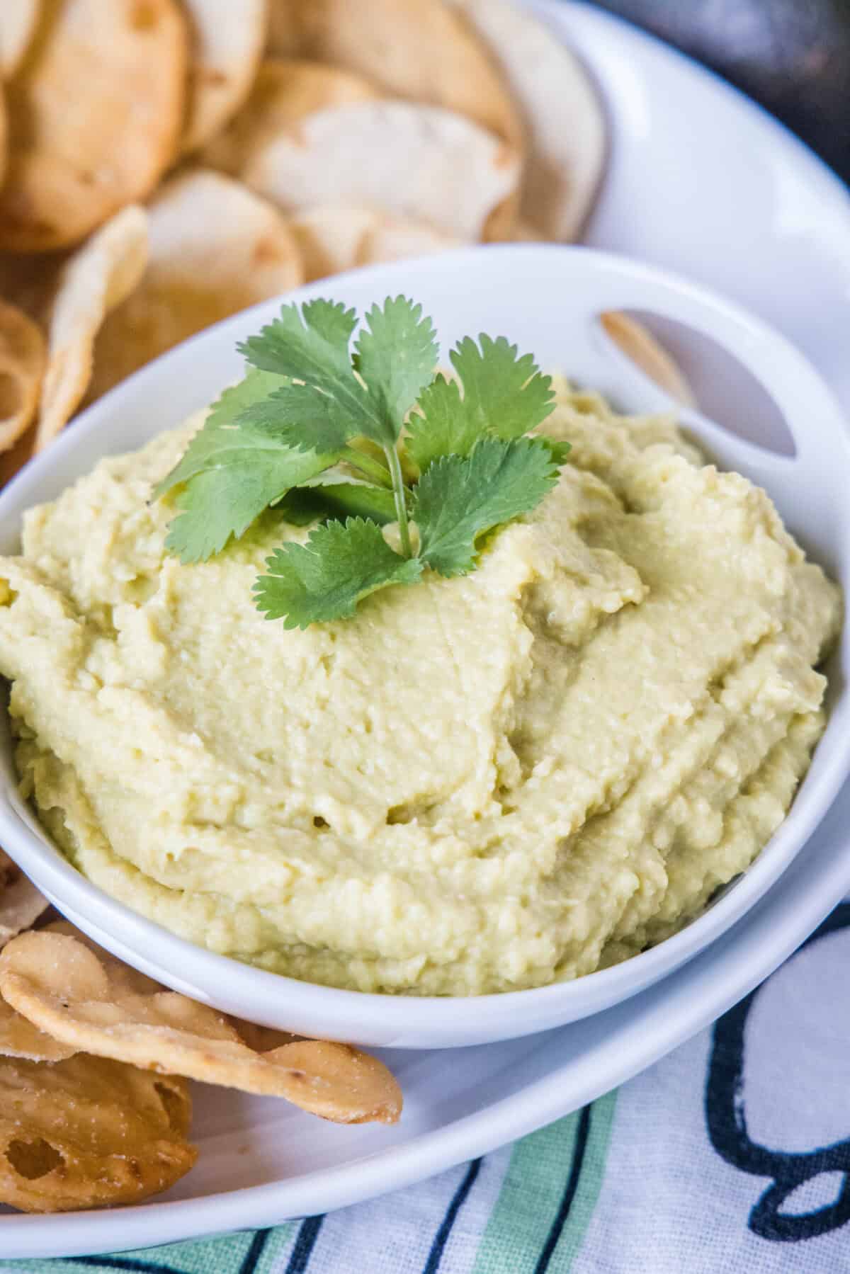 a white bowl with avocado hummus topped with cilantro