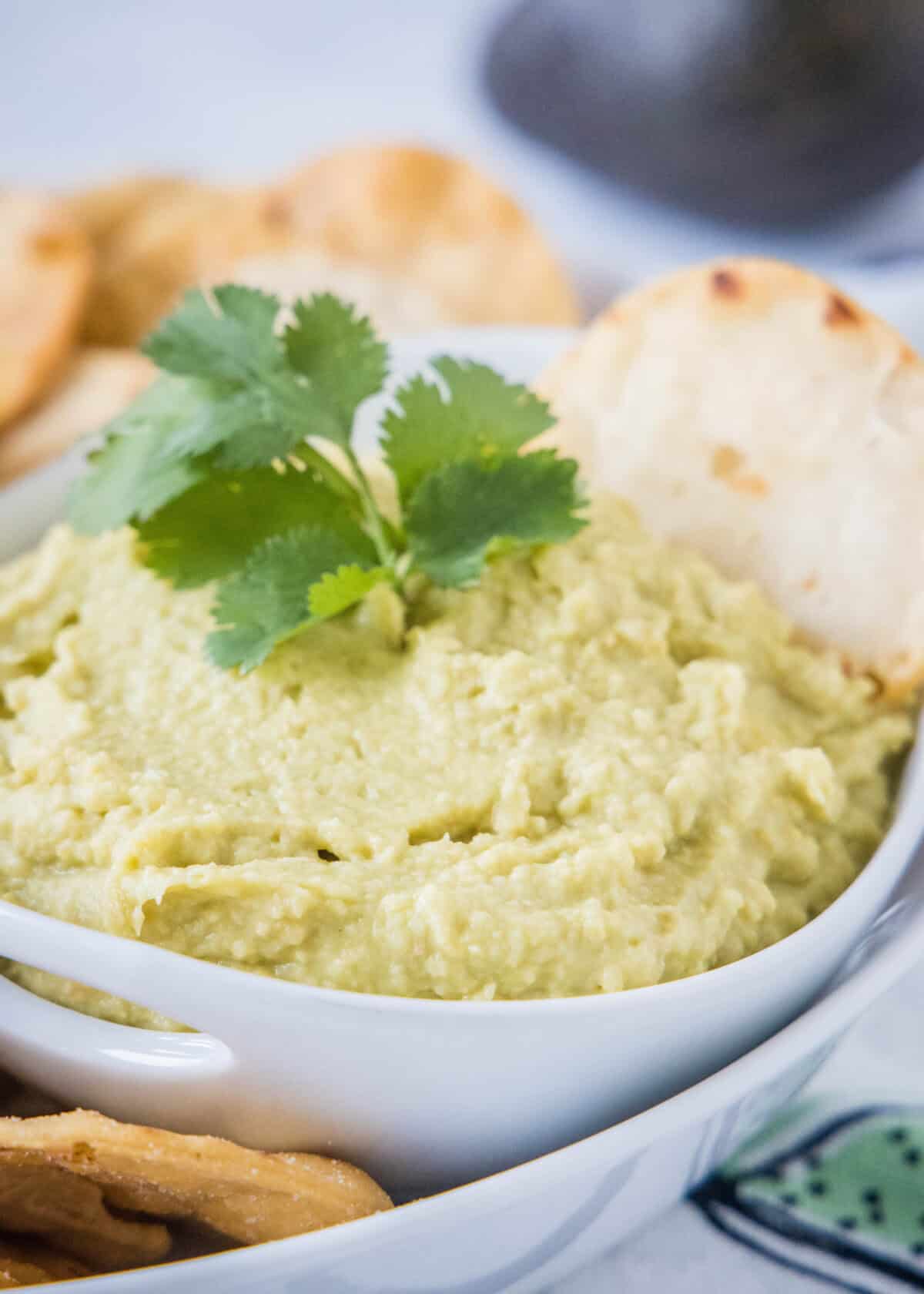 avocado hummus in a bowl wih a cracker