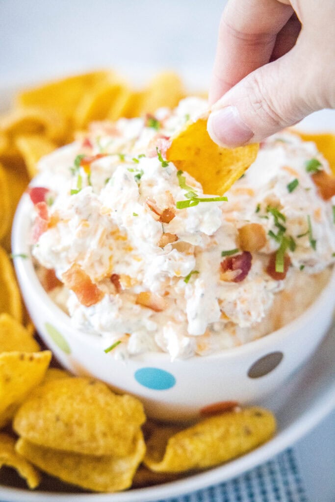 a chip scooping dip out of a bowl