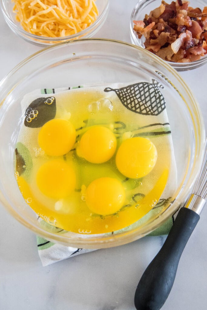 Five eggs cracked into a glass bowl.