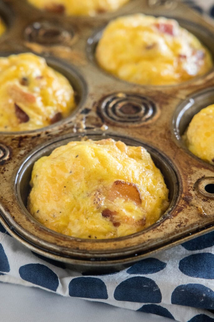 Baked bacon cheese egg muffins in a muffin pan.