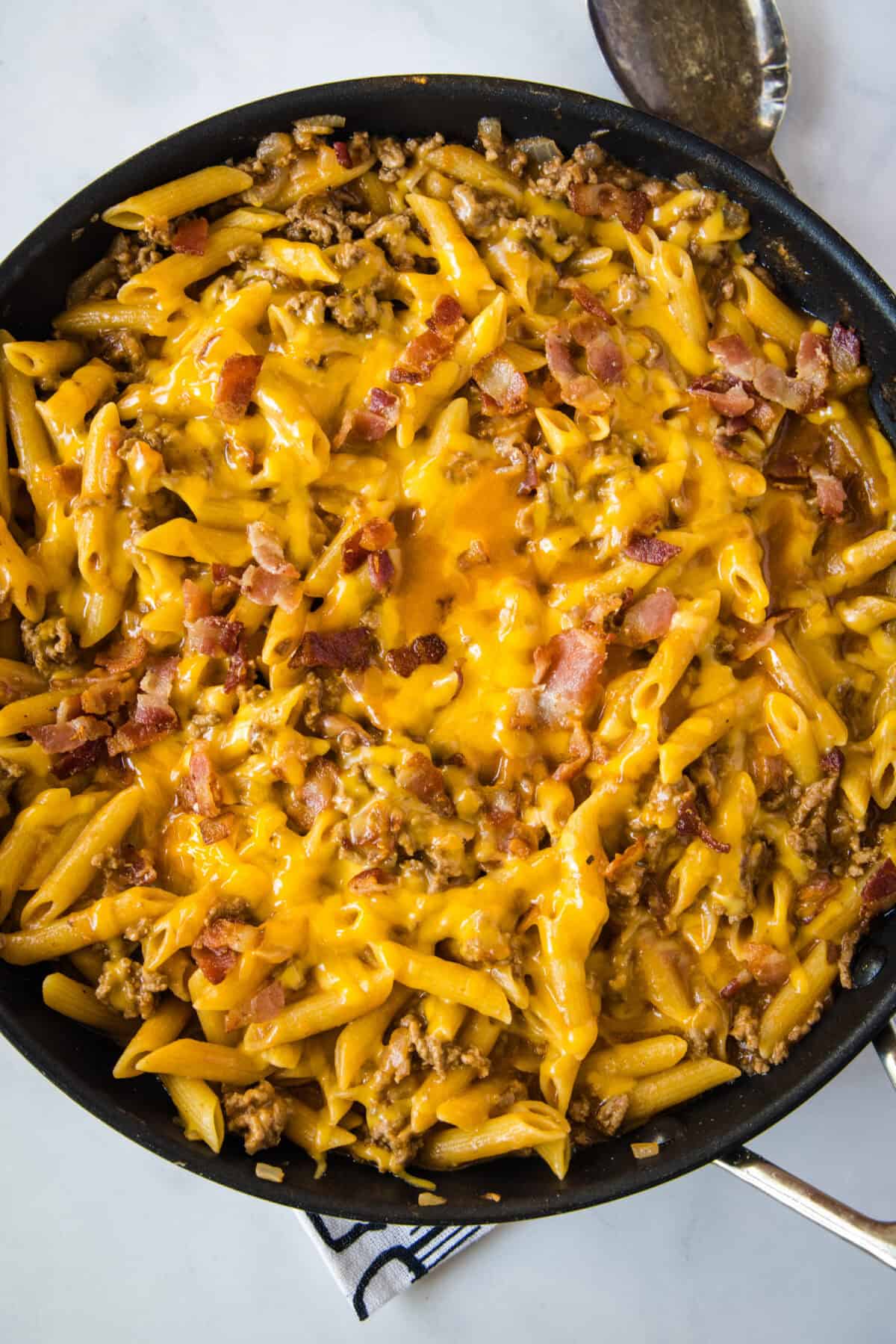 skillet with pasta topped with cheese and bacon