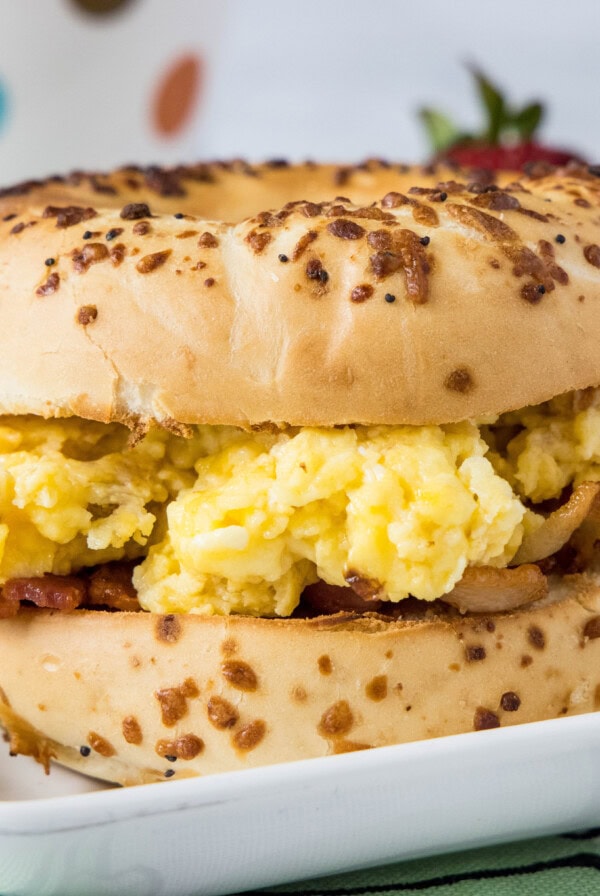 An egg and bacon bagel sandwich on a plate