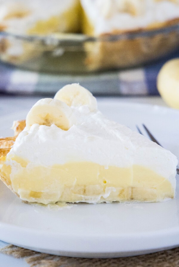 Close up of a slice of banana cream pie on a plate with a fork