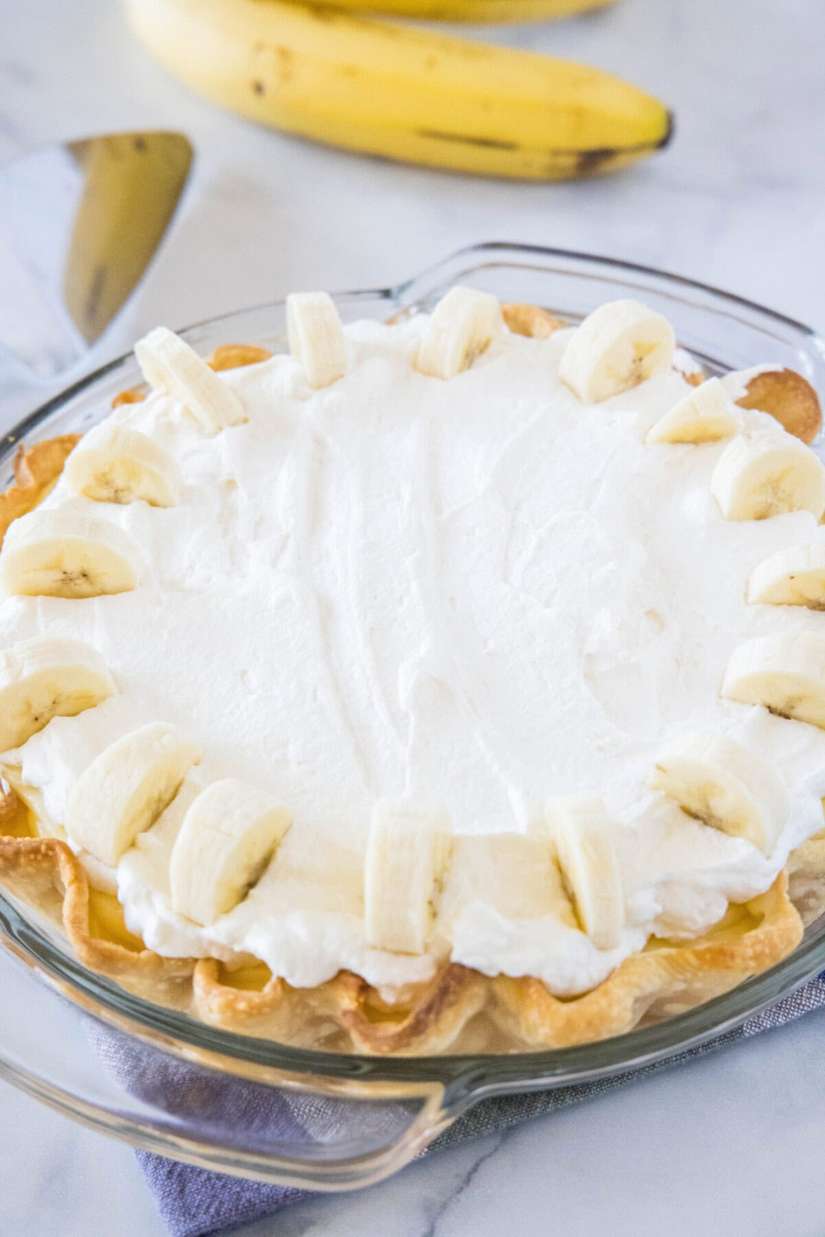 This banana cream pie is rich, decadent, and loaded with banana flavor. It's as good as anything from a bakery, and easy to make. A banana cream pie, with a banana in the background