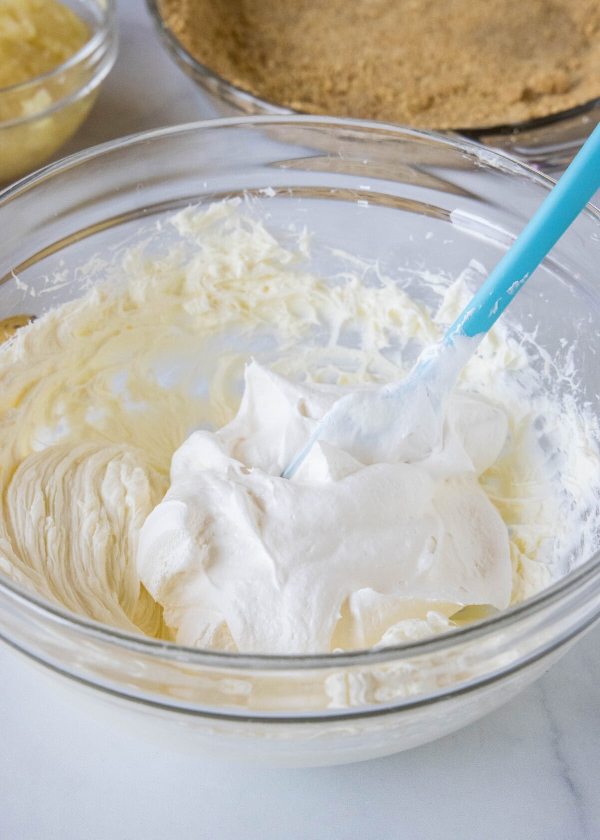 Whipped topping added to cream cheese filling in a bowl.