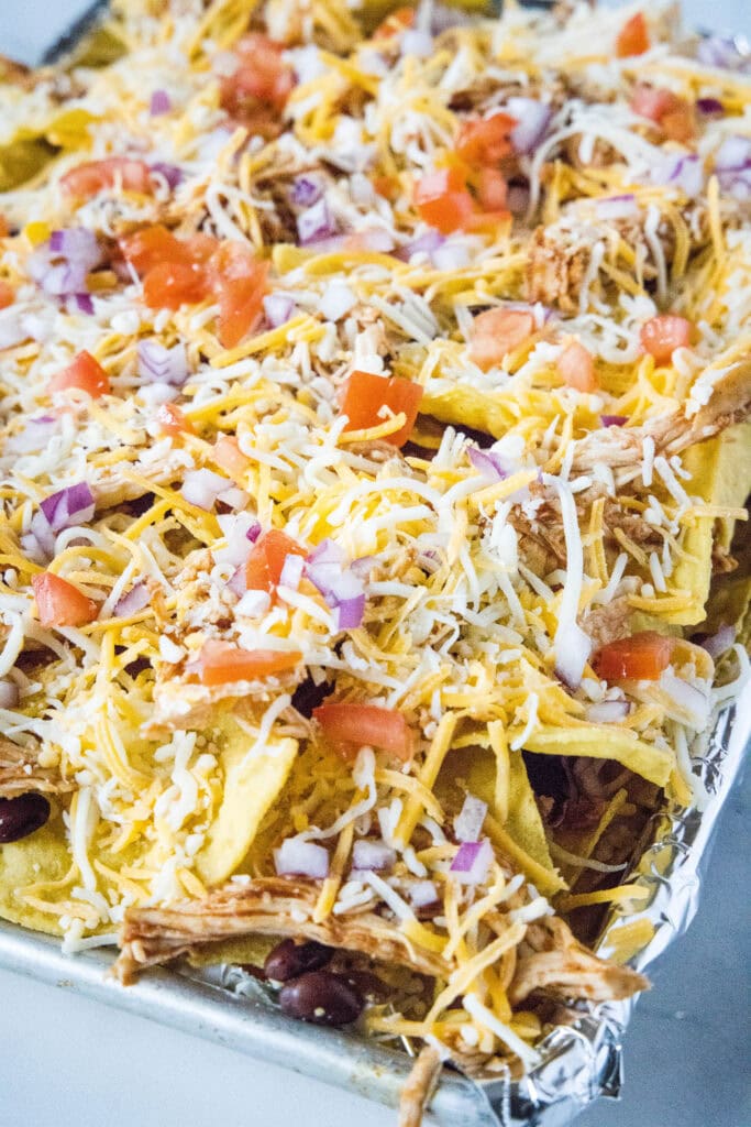bbq chicken nachos on a baking tray ready for the oven