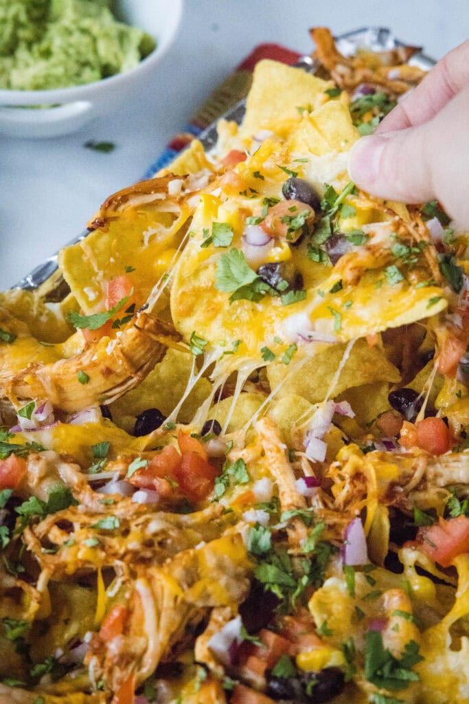pulling a chicken nacho off the tray