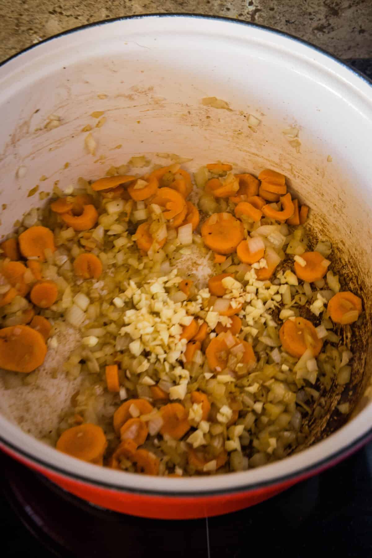 carrots and onions sauteing in a stock pot