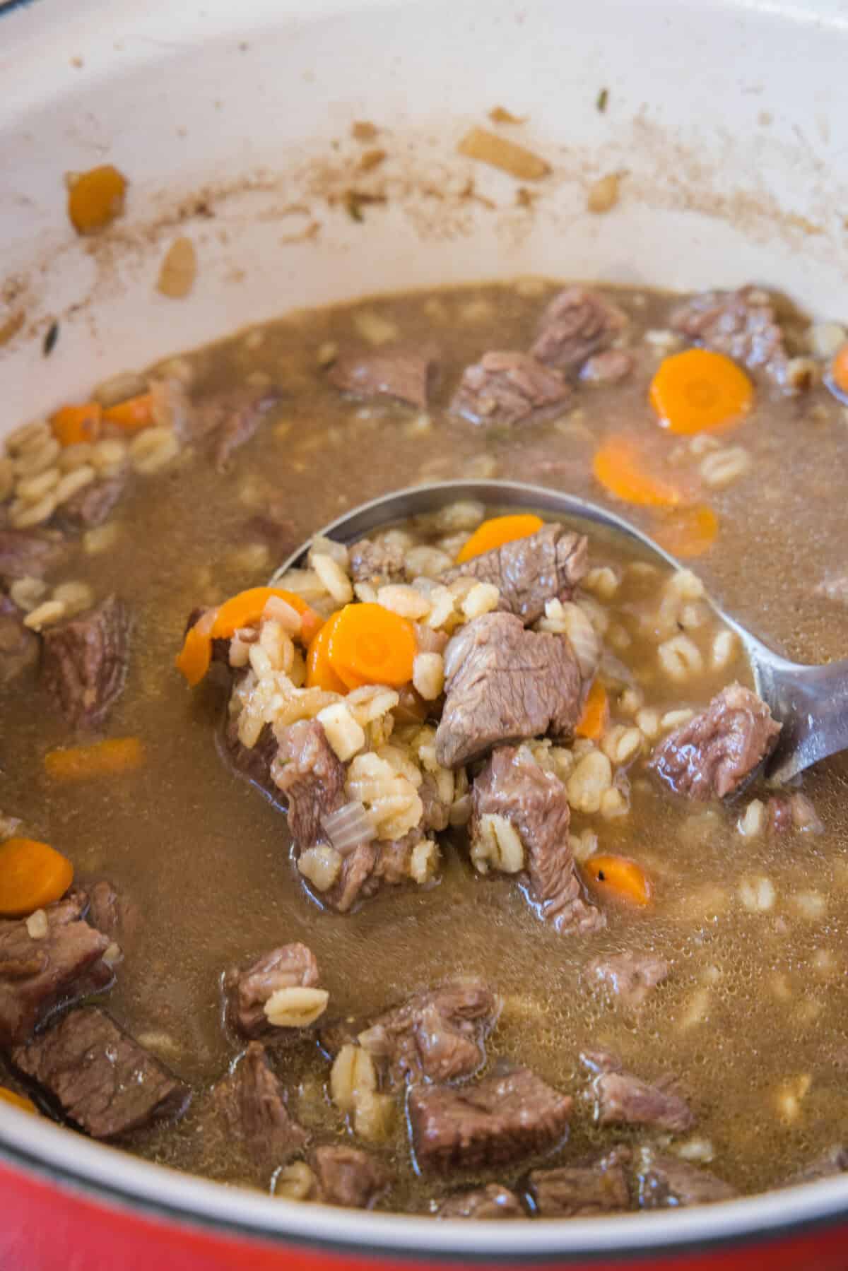 scooping beef barley soup out of stock pot