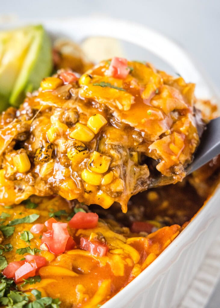 scooping enchilada casserole out of the pan