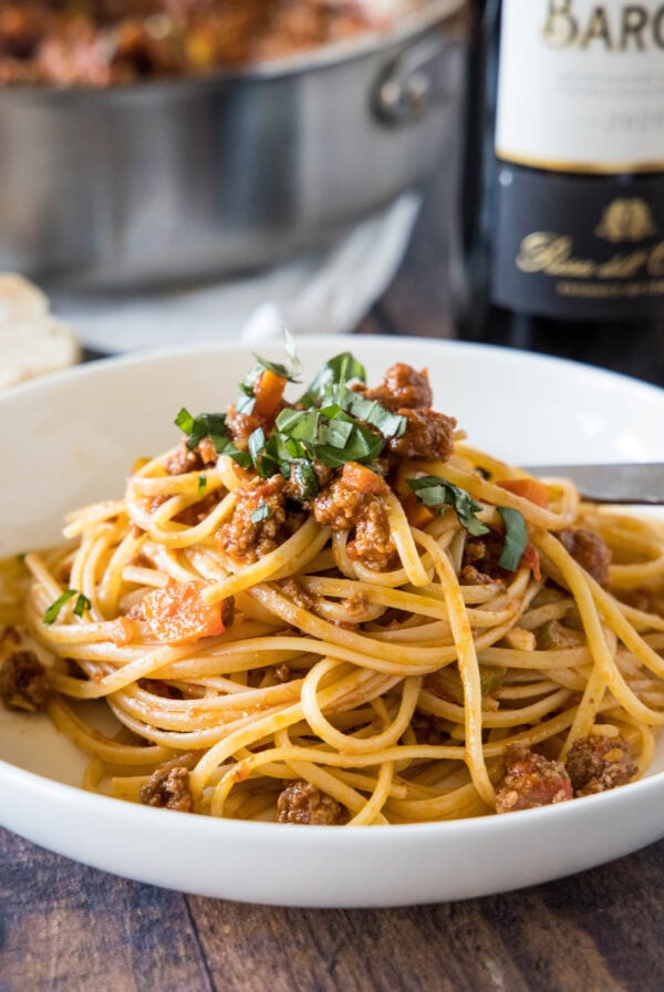 Beef ragu served with spaghetti in a white bowl.