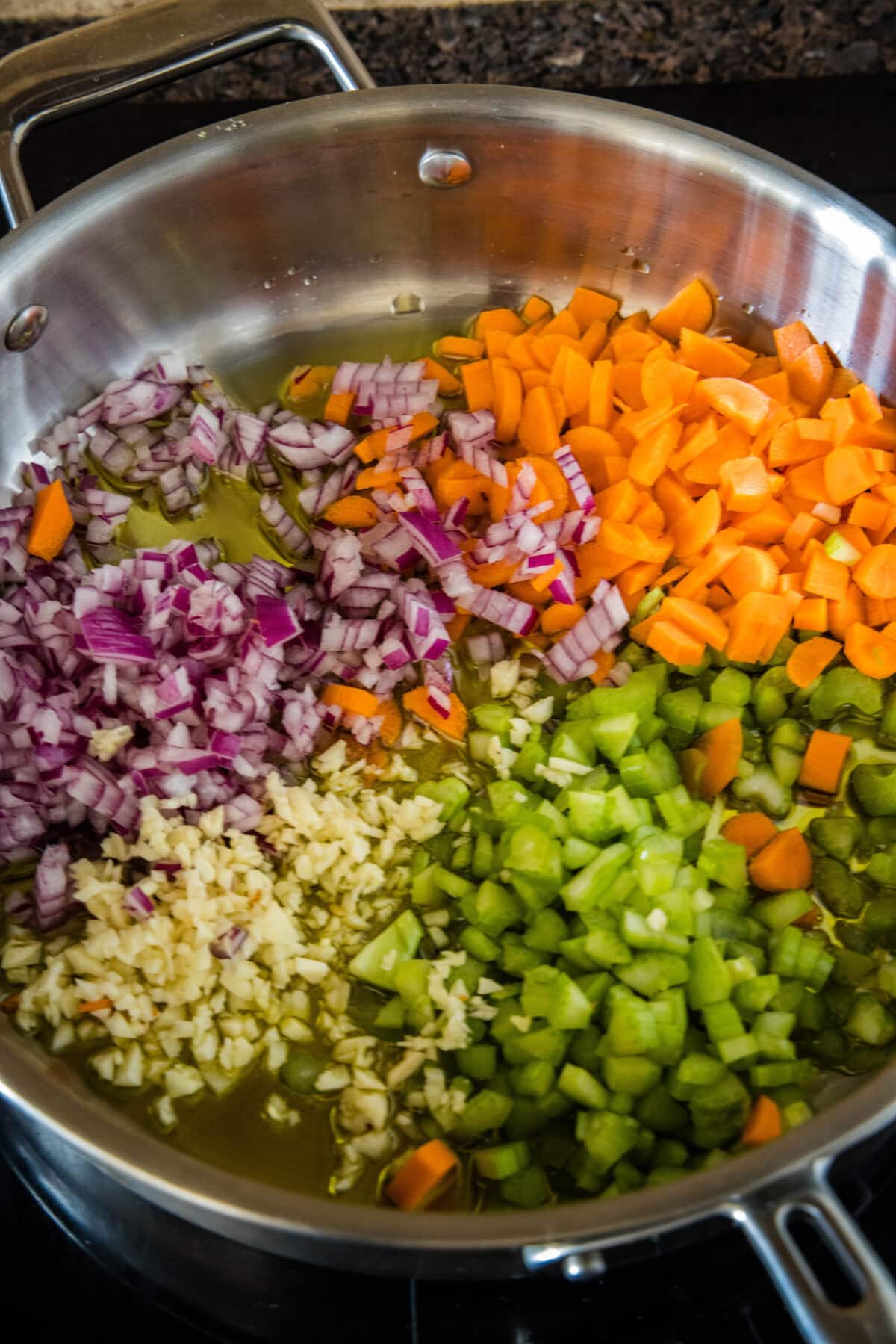 Diced vegetables sauteeing in a skillet.