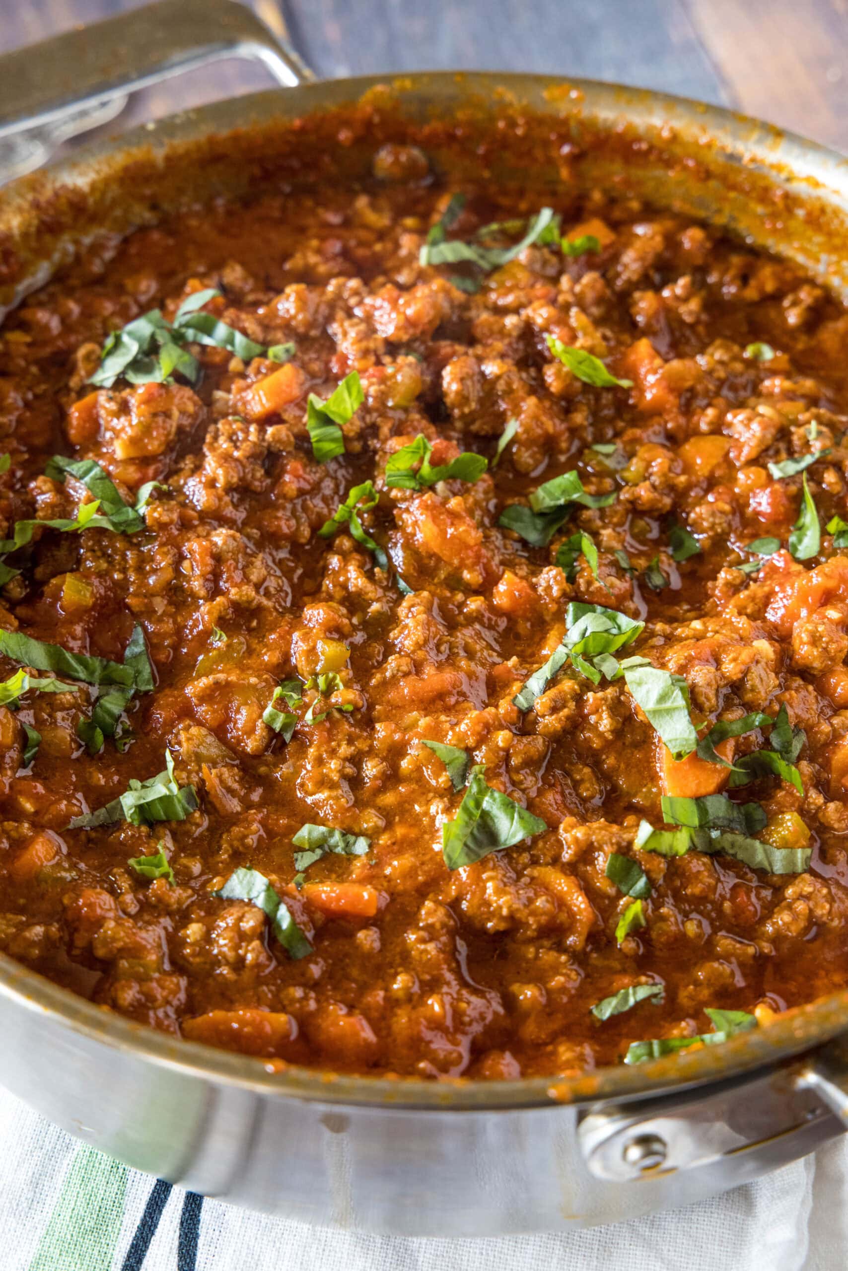 Beef ragu garnished with chopped basil leaves in a large deep skillet.