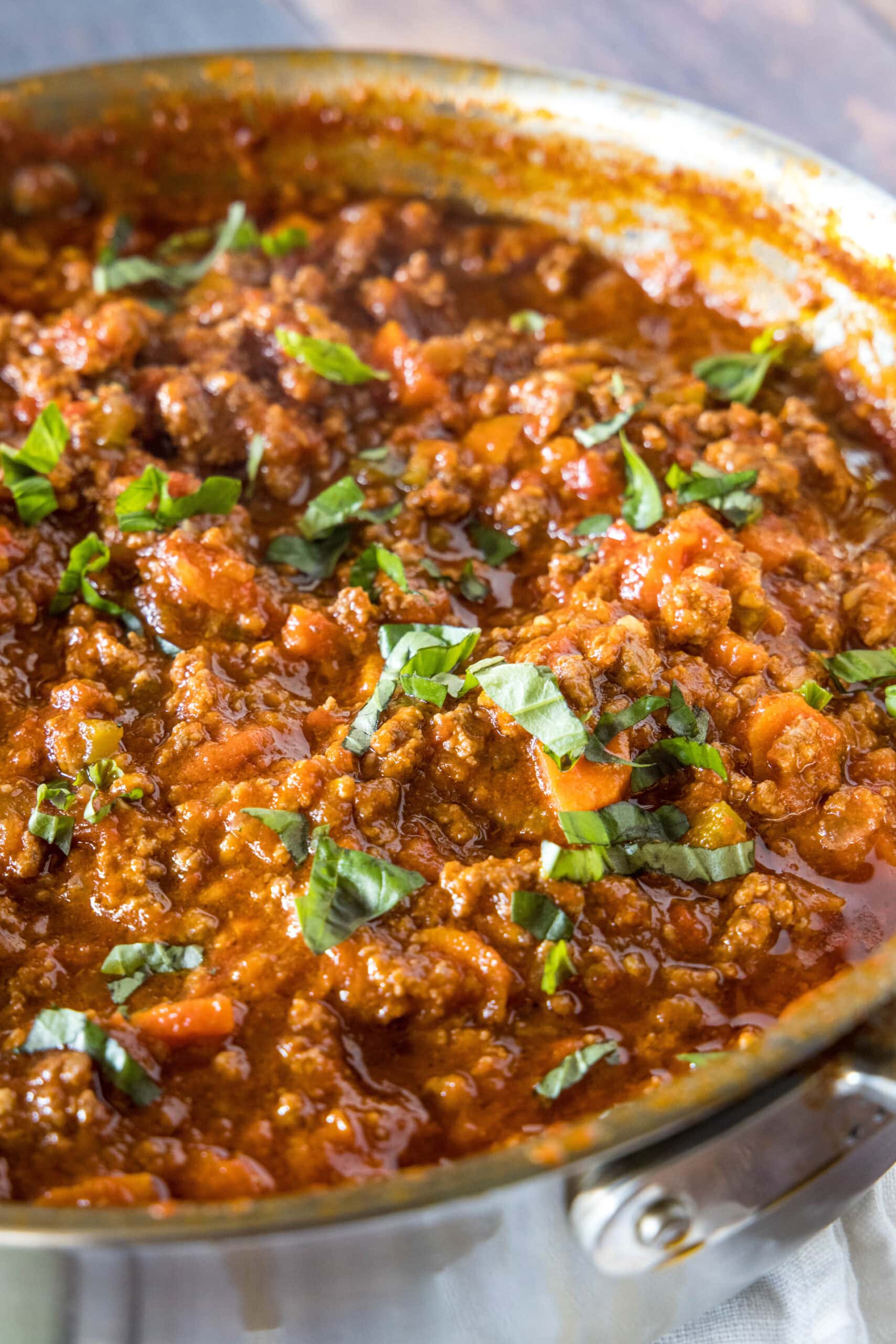 Beef ragu garnished with chopped basil leaves in a large deep skillet.