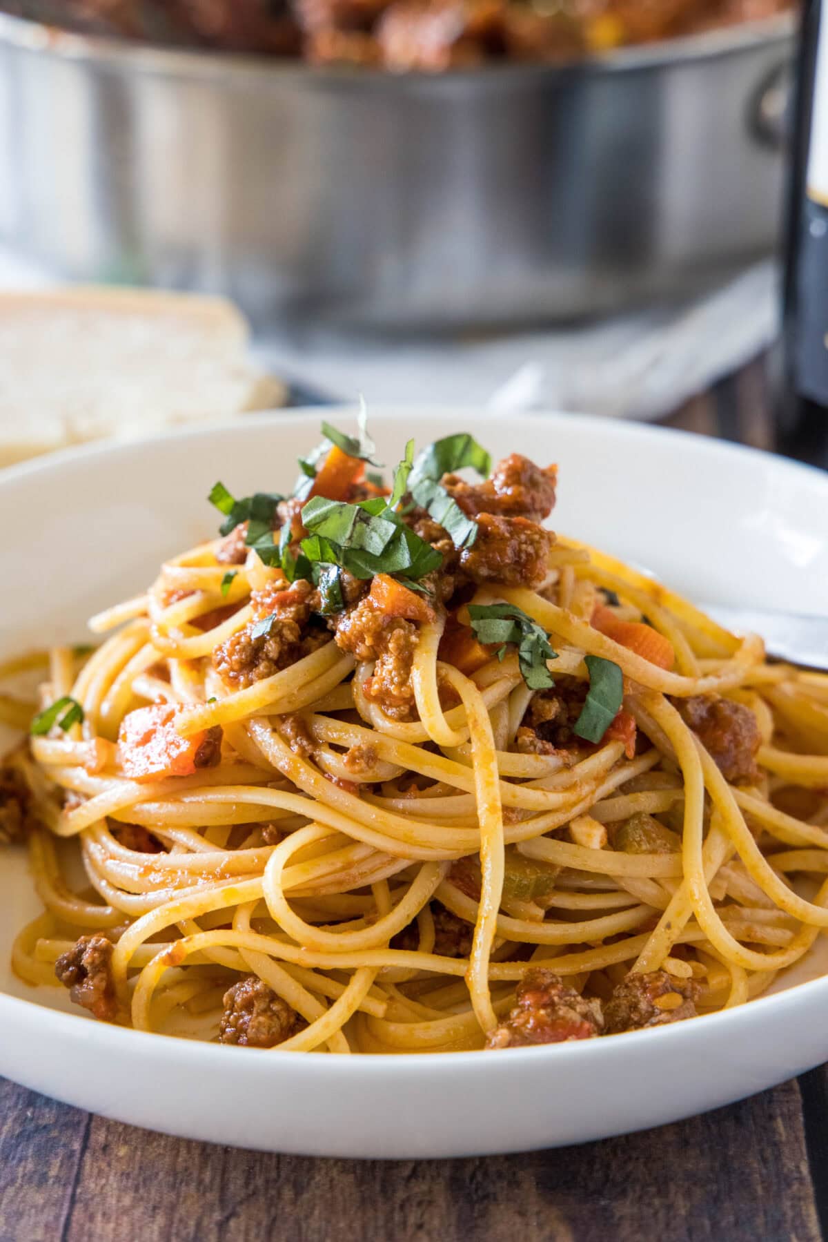 Beef ragu served with spaghetti in a white bowl.