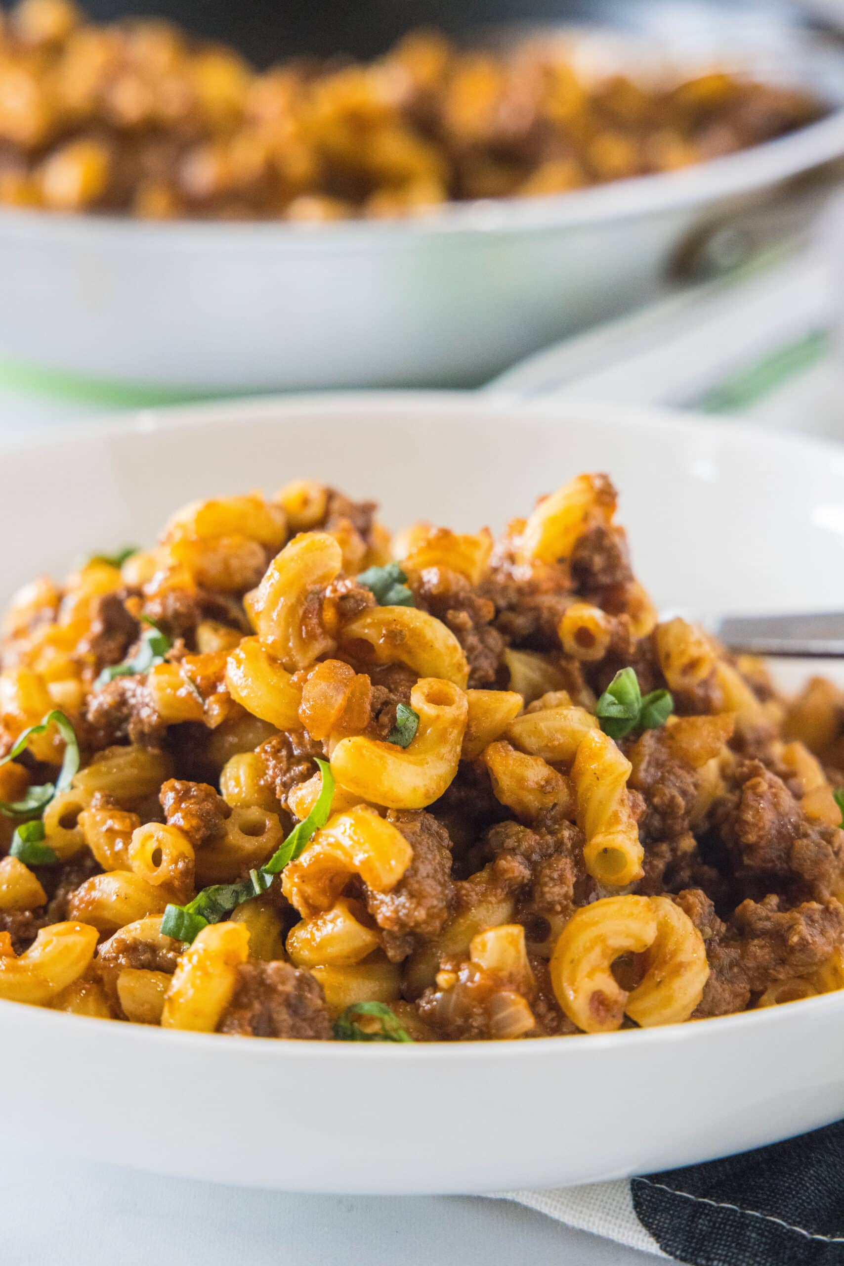 A bowl of beefaroni with another bowl in the background