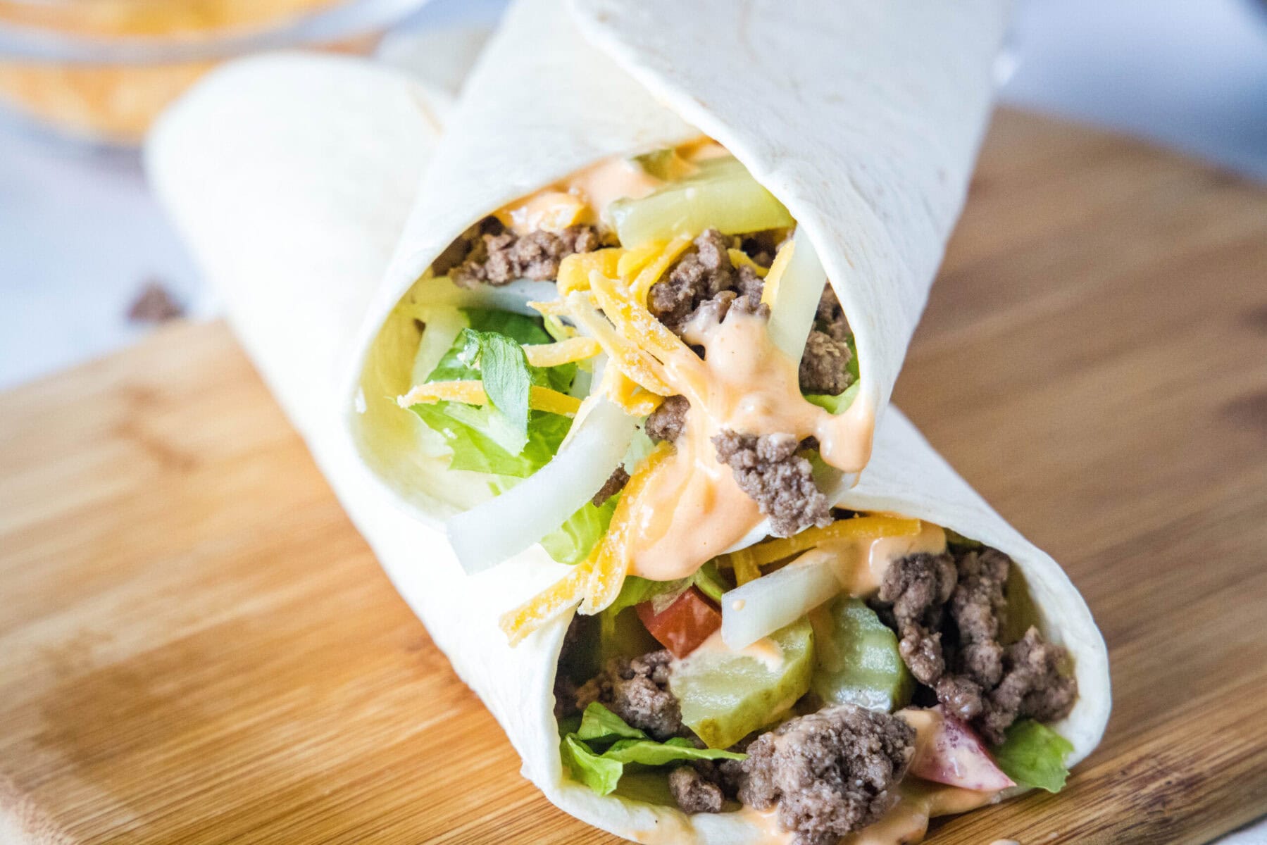 Two burger wraps stacked on top of each other at an angle, on top of a cutting board