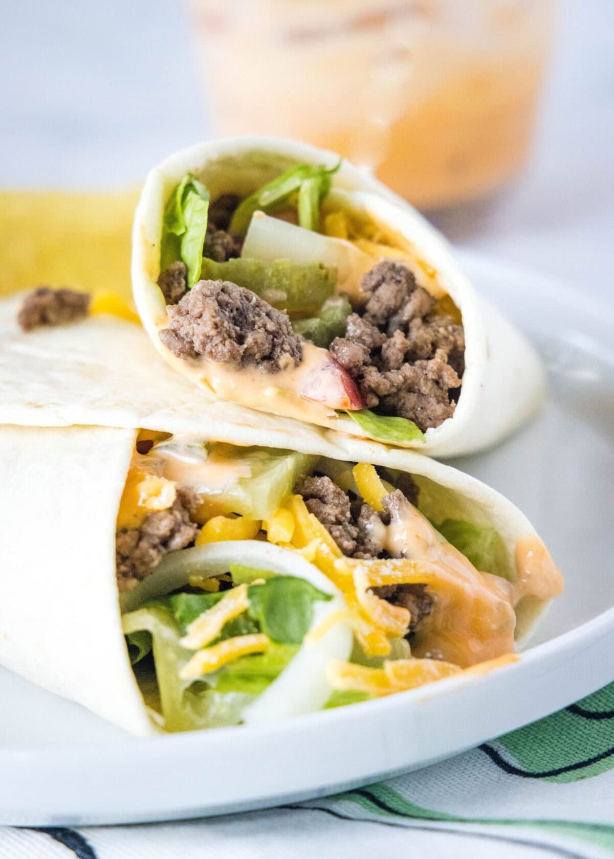 A burger wrap leaning against another burger wrap on a plate