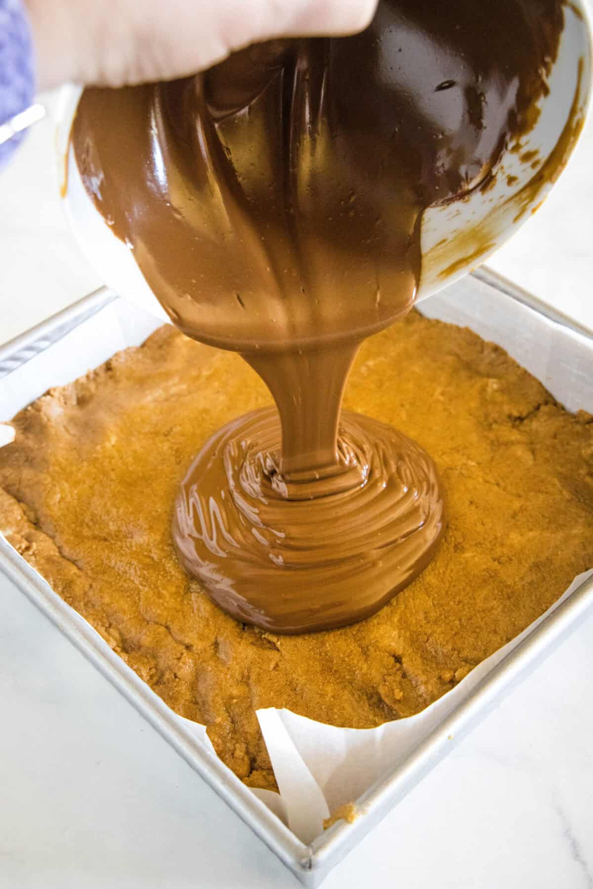 pouring melted chocolate over biscoff bars