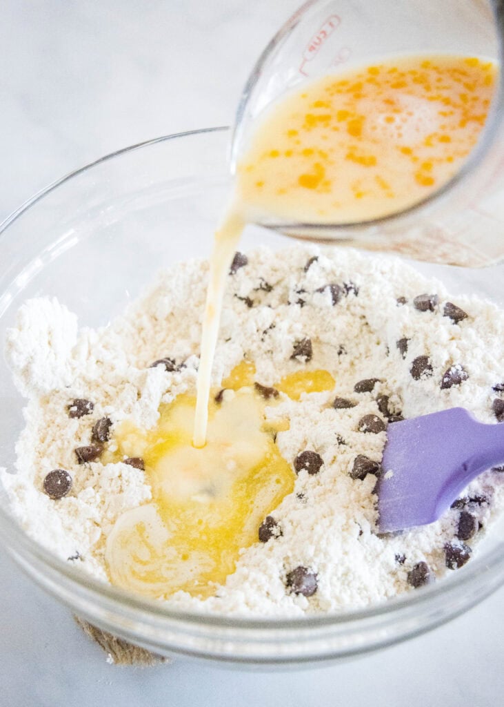 pouring milk and egg into muffin mix in a mixing bowl