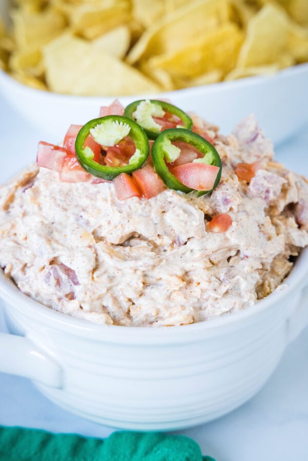 Boat dip topped with sliced jalapeños in a white bowl.