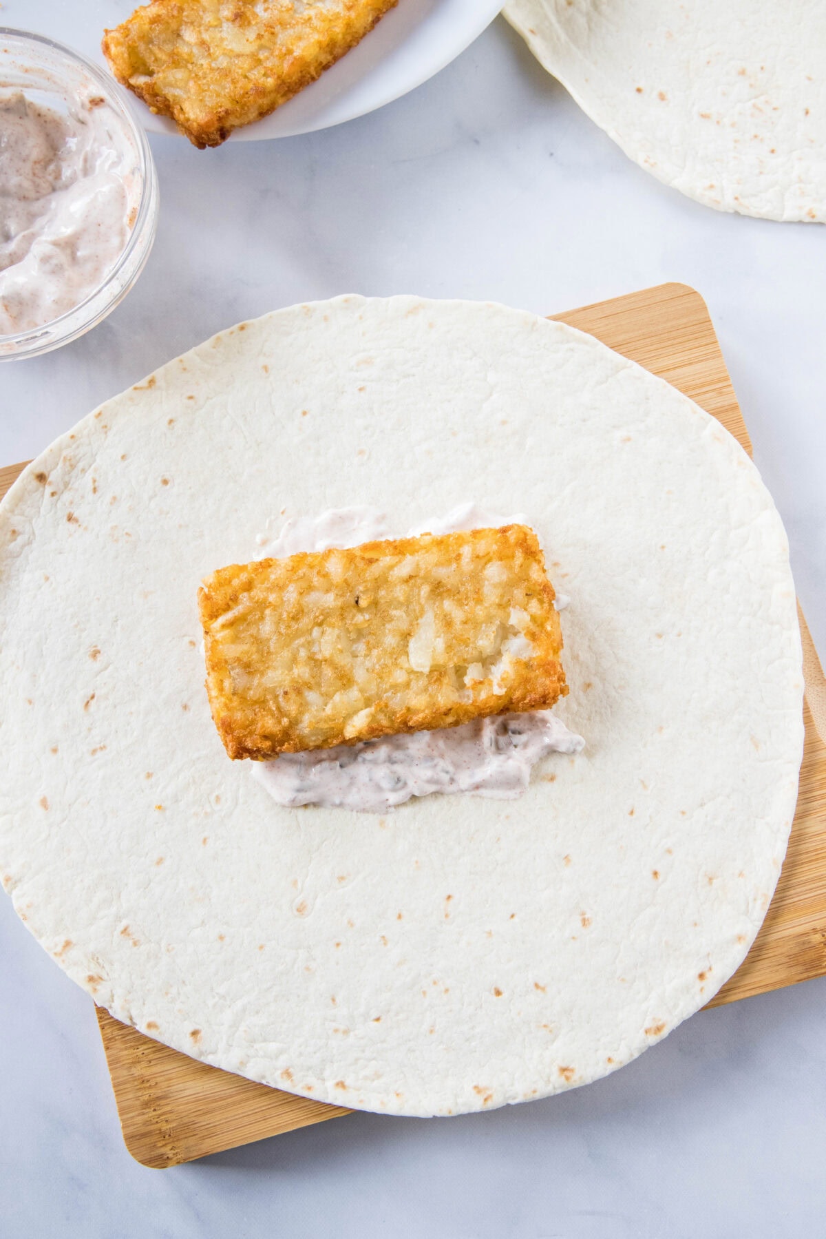 A hashbrown layered over jalapeño sauce in the center of a large flour tortilla.