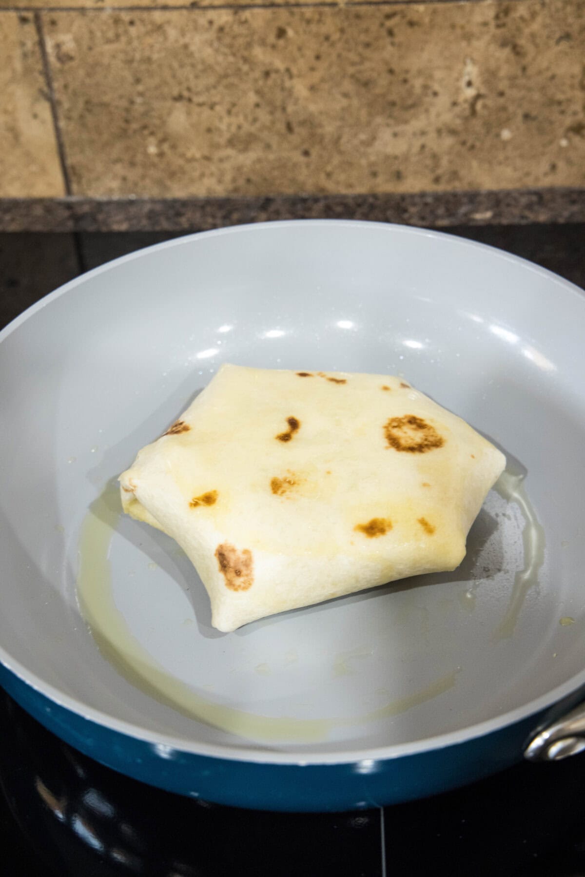 A folded breakfast crunchwrap in a skillet.
