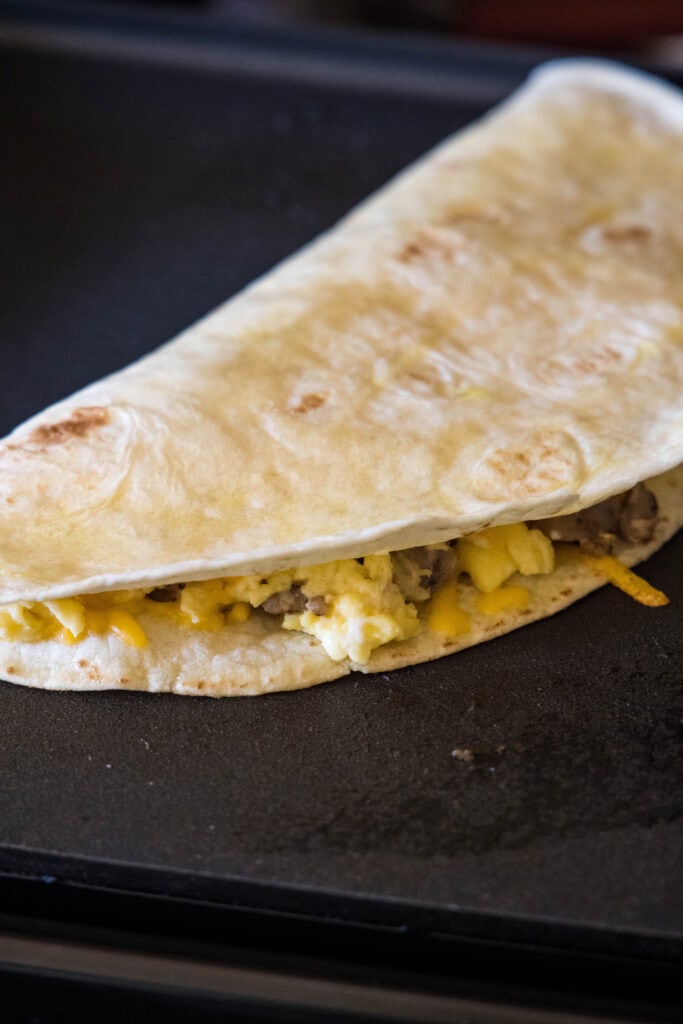 A folded breakfast quesadilla on a griddle.