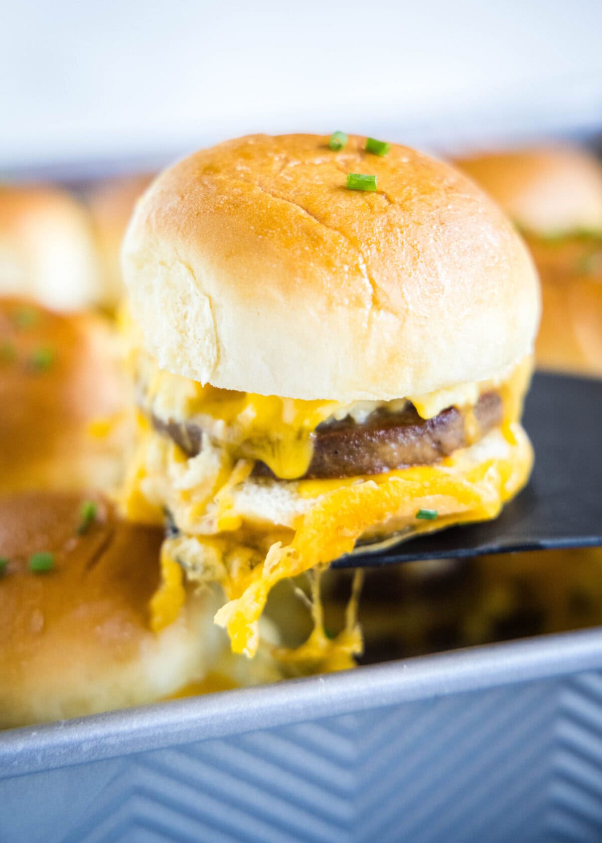 These protein-packed breakfast sliders have all your favorite breakfast flavors in them. They’re loaded with tender scrambled eggs, savory sausage, and gooey cheese, and they’re so easy to make. There are few things in life that are as good as a big and hearty breakfast. A plate of eggs, meat, and toast is just the perfect way to start a day. Lately, I’ve started making breakfast sliders as my go-to breakfast because they combine all of those comforting breakfast flavors that I love so much. These easy egg sliders feature velvety scrambled eggs, hearty and juicy sausage, and melty cheese stuffed between soft and pillowy buns. They’re brushed with maple syrup and butter, just to add even more breakfast flavors to the party. If you love breakfast as much as I do, then you’ve got to try making these easy sausage and egg sliders. Why You’ll Love This Breakfast Sliders Recipe This is the type of breakfast recipe that you can make every week and never get tired of. Here’s why I know you’ll enjoy these sliders as much as I do. Easy. Even though these breakfast sliders taste like they came out of a restaurant, they’re really easy to make. All you have to do is heat up some sausage, scramble some eggs, assemble the sliders, and bake. It doesn’t get much more simple than that! Full of protein. This is the perfect recipe to start your day with. Egg sliders are filled with meat, eggs, milk, and cheese, so they’re packed full of protein. Eat one of these savory and meaty sliders in the morning and you’ll have energy all day long. Packed with breakfast flavors. Everybody loves breakfast. And this recipe has all of your favorite breakfast flavors in every bite. What’s not to love? On-the-go breakfast. One of the best things about this recipe is that you can easily take it on the go. If you’re running out the door to start your day, you can grab a cheesy egg and sausage breakfast slider for the road. What You’ll Need Here are all the ingredients you’ll need to make these protein-filled breakfast sliders. Make sure to scroll to the recipe card at the end of the article to see the exact amounts of each ingredient. Slider buns Sausage patties – Use whatever type of sausage you prefer. Eggs Milk Salt Pepper – Always use freshly cracked pepper. Shredded cheddar cheese – For best results, shred your own cheese. Butter Maple syrup – This is an optional ingredient. Chives – Chives are used as an optional garnish. Recipe Variations These easy breakfast sliders use all of my favorite breakfast flavors. But you can adjust the recipe to include other classic breakfast flavors, too. Here are a few variations you can try. Different meat. I like these sliders best with breakfast sausage, but you can use other meats as well. They’d be fantastic with bacon or Canadian bacon. Add hot sauce. Breakfast foods are perfect to put hot sauce on. If you’re a fan of spiciness, you can add some hot sauce on top of the eggs when you make this recipe. Include hash browns. Potatoes are obviously a classic breakfast food as well, and they go so well with eggs and meat. If you want to add some potato flavor to this recipe, simply place a layer of hash browns on top of the sausage patty. Swap the buns for mini waffles. If you want to make these egg and sausage sliders look like something on a trendy restaurant’s menu, you can use mini waffles in place of slider buns. That will bring the breakfast flavors to a whole new level. Make vegetarian. This is an easy recipe to make vegetarian. All you have to do is remove the sausage or replace it with vegetarian sausage. You can also swap out the meat for tomatoes or avocado. How to Make Breakfast Sliders These rich breakfast sliders with tender and moist scrambled eggs are so easy to make. Here’s how to do it. Prep. Preheat your oven to 350F. Cook the meat. Brown the sausages in a skillet until they’re fully cooked. Prepare the buns. While the sausage is cooking, place the bottoms of the slider buns in a 9-inch baking dish. Sprinkle half of the cheese on top of the buns. Add the meat. Place one sausage patty on top of each slider bun. Scramble the eggs. Add the eggs and milk to a bowl, and season to taste with salt and pepper. Wipe most of the grease out of the skillet, then pour in the eggs. Scramble while stirring frequently until the eggs are mostly set. Assemble. Put the scrambled eggs on top of the sausage patties, then add the rest of the shredded cheese. Place the slider buns on top of the cheese. Brush. Combine the melted butter with the maple syrup, and brush it over the top of the slider buns. Bake. Put the sliders in the oven and bake until the cheese is melted and the buns are golden brown, about 18-20 minutes. Serve. Remove the breakfast sliders from the oven, top with chives, and serve while hot. Tips for Success Here are a few tricks and tips to follow when you make these savory breakfast sliders. Don’t overcook the eggs. It’s really important to take the eggs off the stove before they’re fully cooked. This will keep the eggs from overcooking and becoming rubbery and dry when you bake the sliders. Brown the meat. When you cook the sausage, make sure you get a nice sear on the meat. Browning meat maximizes the flavor, so be sure to use a pan that’s hot enough to sear the sausage. Keep an eye on the sliders. Make sure to check the sliders after about 10 minutes in the oven. Some ovens don’t heat very evenly, so check to see if the sliders are cooking more on one side than on the other. If they are, simply rotate your pan. What To Serve With Egg Sliders I usually serve breakfast sliders with some other traditional breakfast dishes or drinks. Here are a few recipes that I think go really well with these rich and savory sliders. Air Fryer Hash Browns Banana Nut Muffins Cinnamon Scones Berry Fruit Salad Mango Smoothie Can These Breakfast Sliders with Sausage Be Prepared In Advance? Absolutely! If you want to have a super quick and easy breakfast, just prepare the sliders the night before. Assemble the cheesy egg sliders and cover them in plastic wrap or aluminum foil, then keep them in the fridge overnight. Then bake them in the morning when you’re ready to eat! How to Store & Reheat Leftovers Leftover egg and sausage sliders will last in the fridge for 3 days, as long as you store them in an airtight container. Reheat in the microwave in 20-second increments until warm throughout. More Easy Breakfast Ideas Whether you prefer savory or sweet, there are so many amazing foods to eat when you start your day. Here are some more of my favorite breakfast recipes. Bacon Egg and Cheese Sandwich Buttermilk Pancakes Breakfast Enchiladas Eggnog Cinnamon Rolls Blueberry Breakfast Cake Breakfast Tacos A spatula removing a breakfast slider from a tray