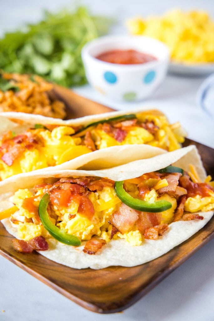 breakfast tacos with bacon on a wood plate