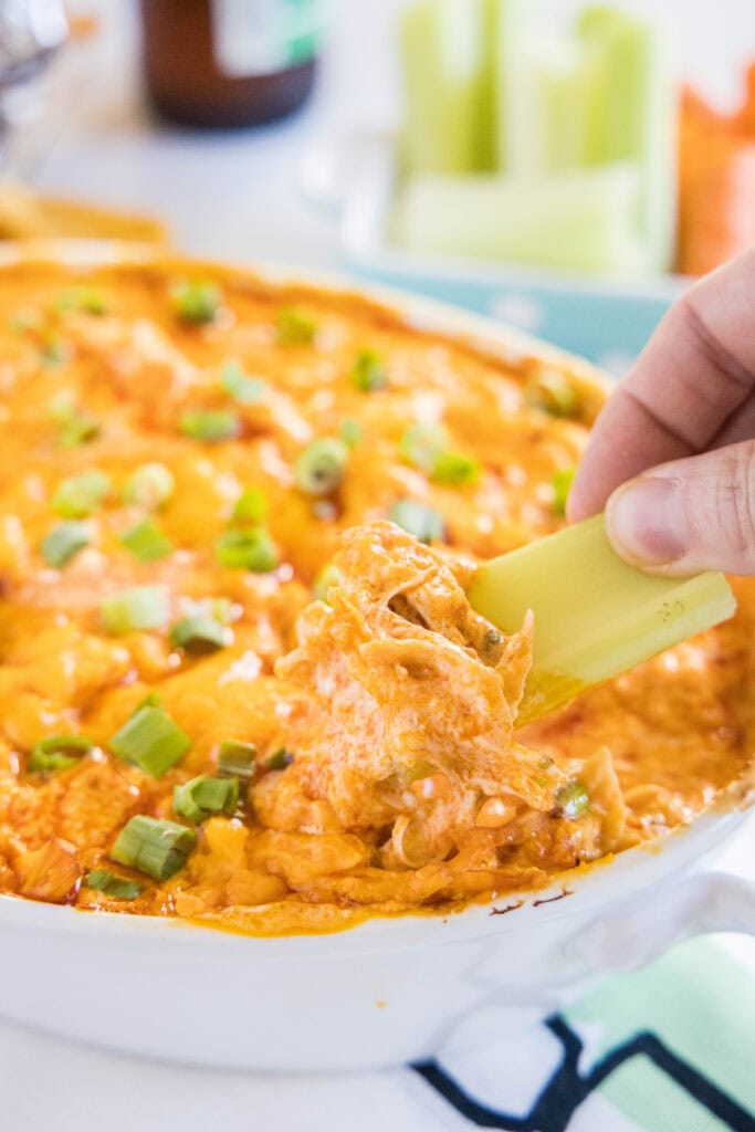 dipping celery into buffalo chicken dip