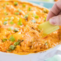 close up dipping celery into buffalo chicken dip
