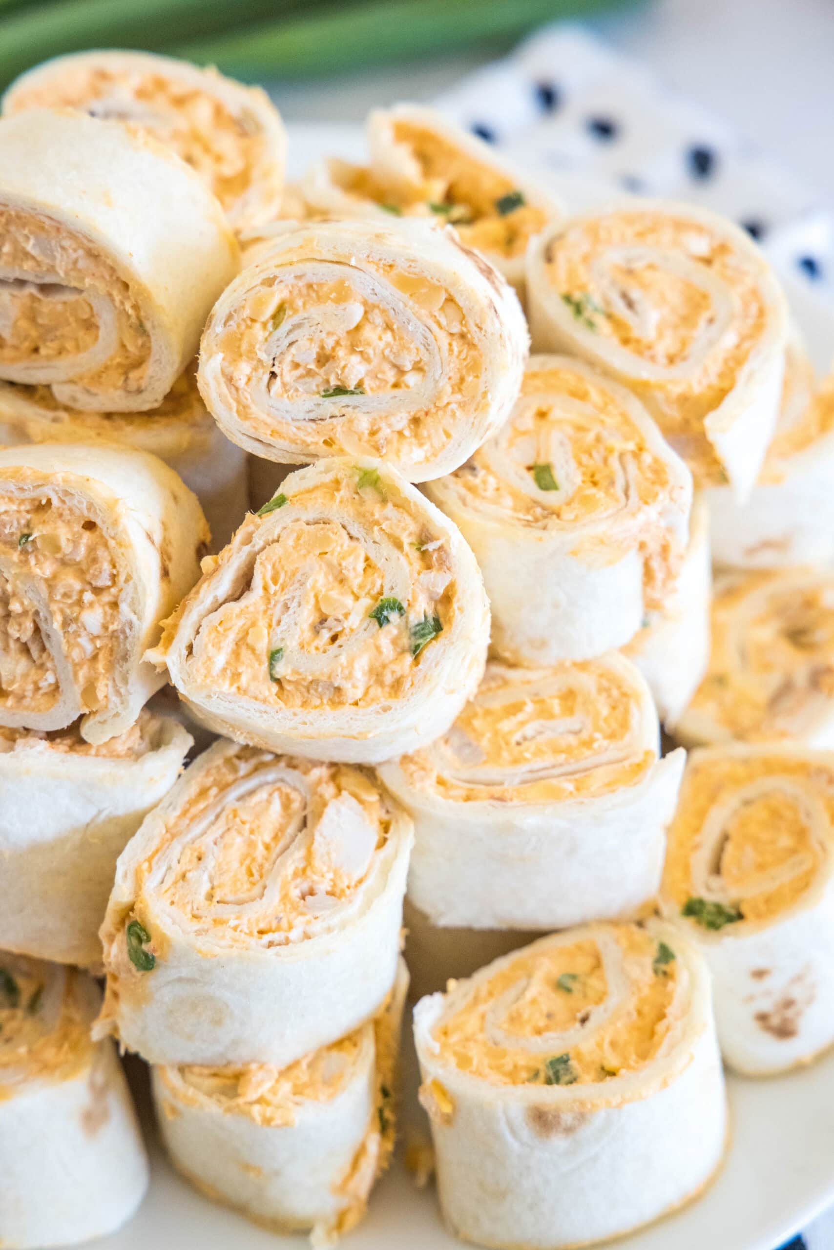 Buffalo chicken pinwheels stacked on a white plate.