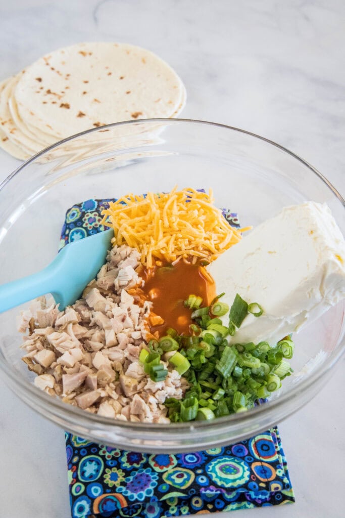 Ingredients for the Buffalo chicken filling combined in a glass bowl.