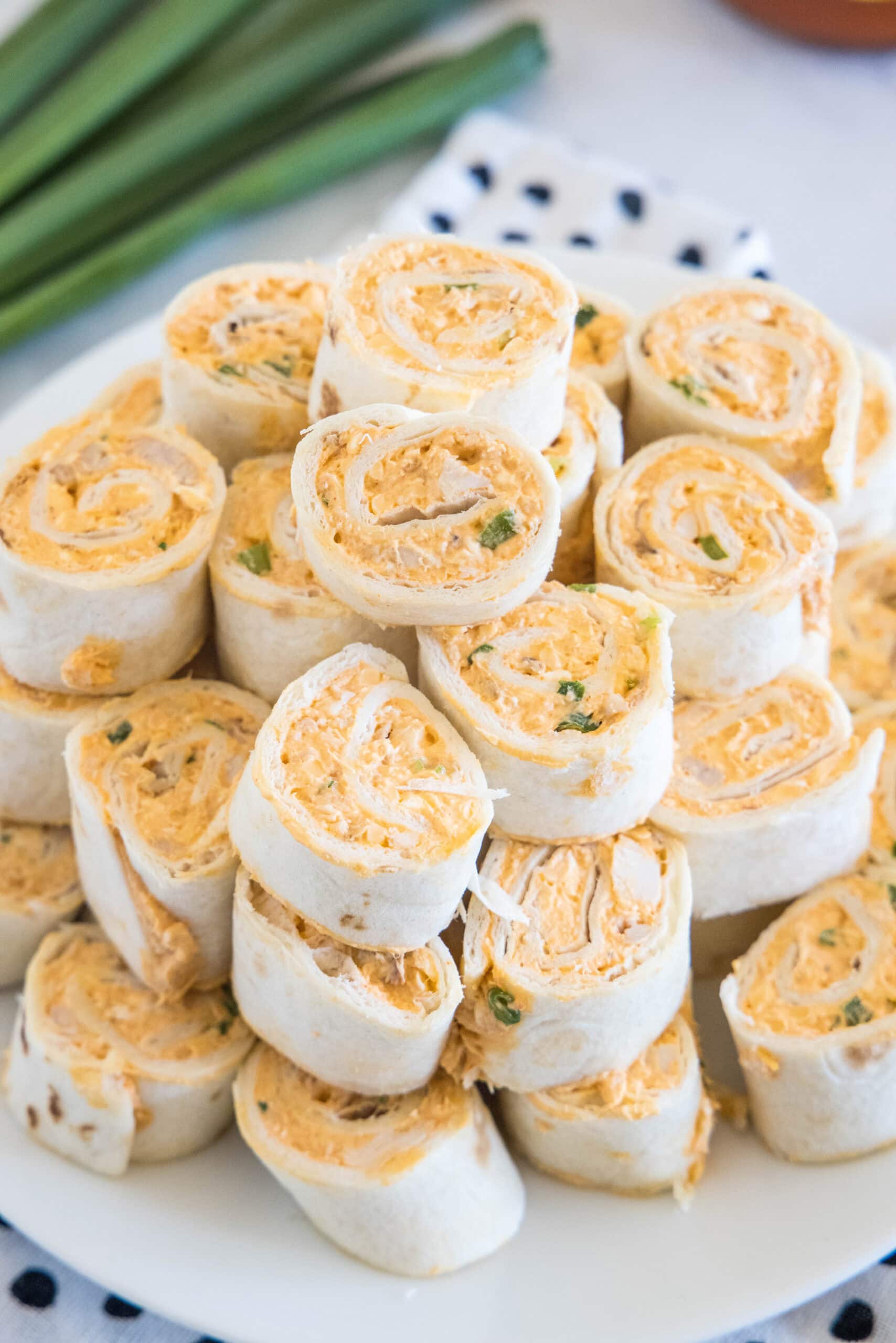 Buffalo chicken pinwheels stacked on a white plate.