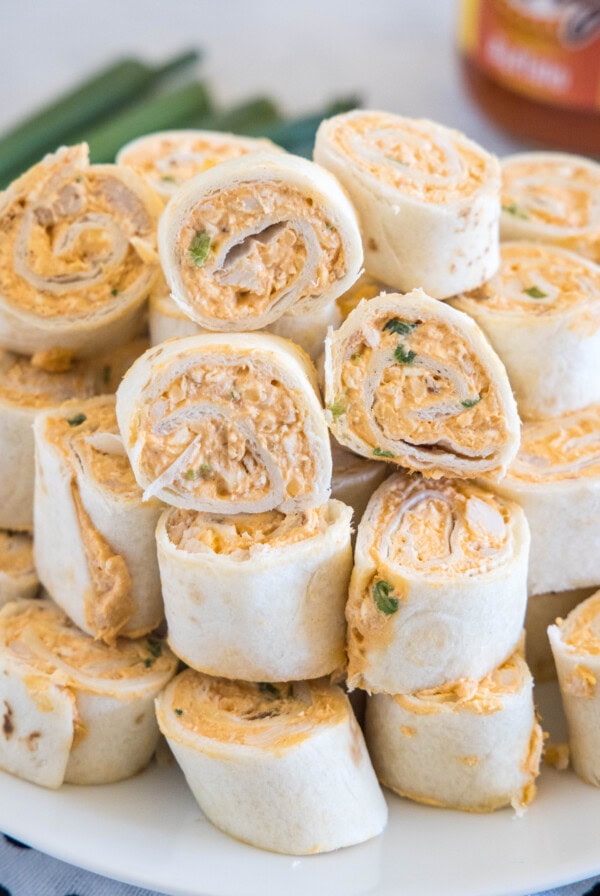 Buffalo chicken pinwheels stacked on a white plate.